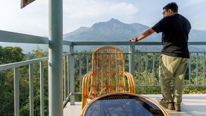 Una persona parada en un balcón con vistas a montañas y vegetación.