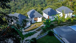 Zona residencial con varias casas, rodeada de abundante vegetación y un paisaje montañoso.