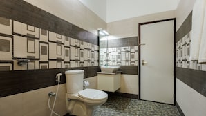 Un baño con inodoro, lavamanos y ducha. Las paredes presentan un diseño de azulejos con motivos geométricos.