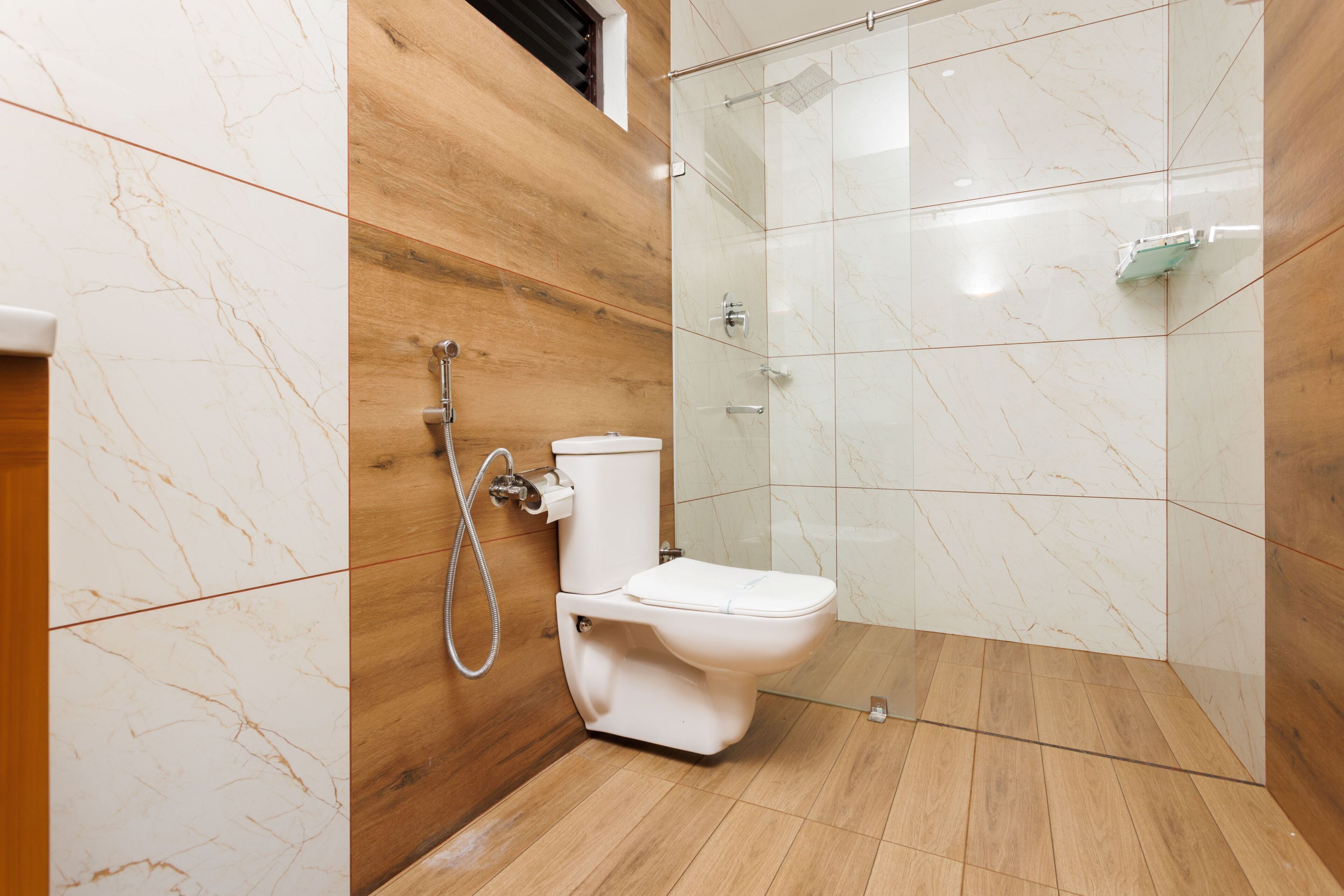 A modern bathroom with a shower, toilet, and wooden paneling.