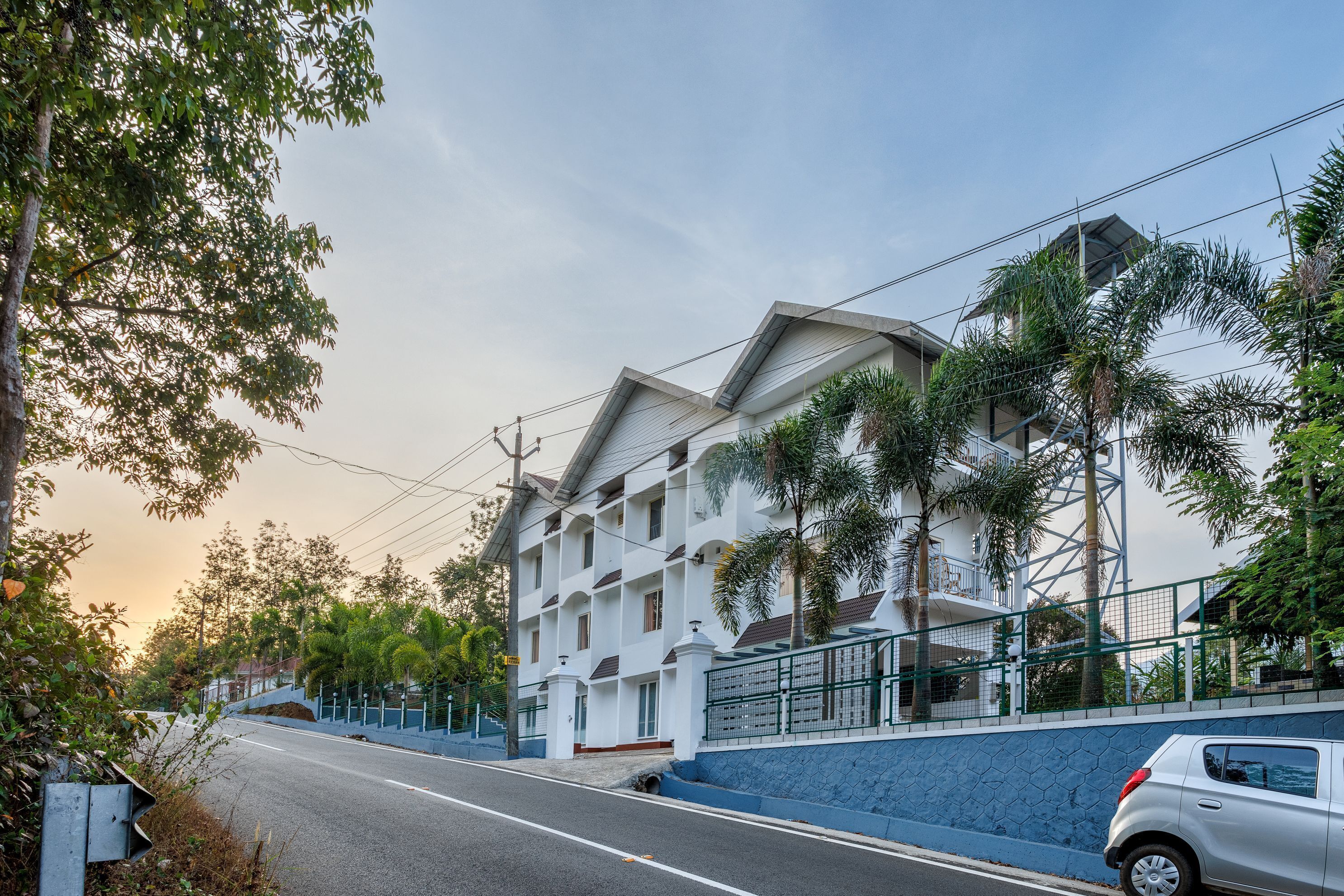 A multi-story building with a white facade, a blue lower section, and a gated entrance.