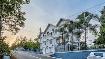 Un edificio de varios pisos con fachada blanca, sección inferior azul y entrada portonada.