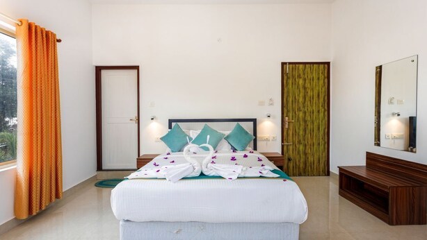 Una habitación de hotel con una cama, un banco de madera, un espejo y una puerta.