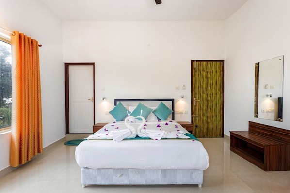 A hotel room with a bed, a wooden bench, a mirror, and a door.