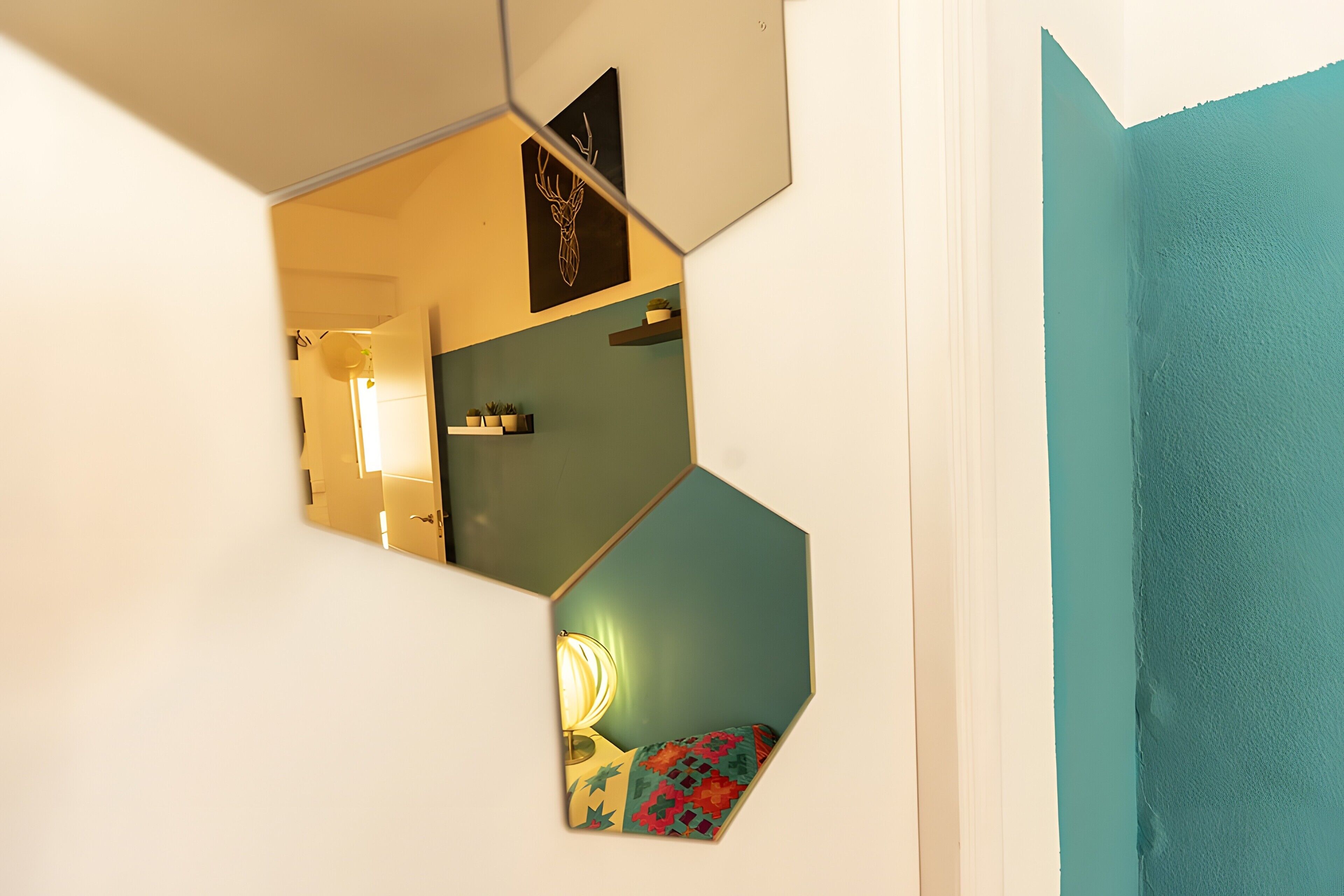 Ein Zimmer mit geometrischem Wanddesign, einer Tür mit einem türkisblauen Einsatz und einem gemusterten Kissen auf dem Boden.