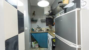 Eine kompakte Küche mit Waschmaschine, Mikrowelle und Kühlschrank.