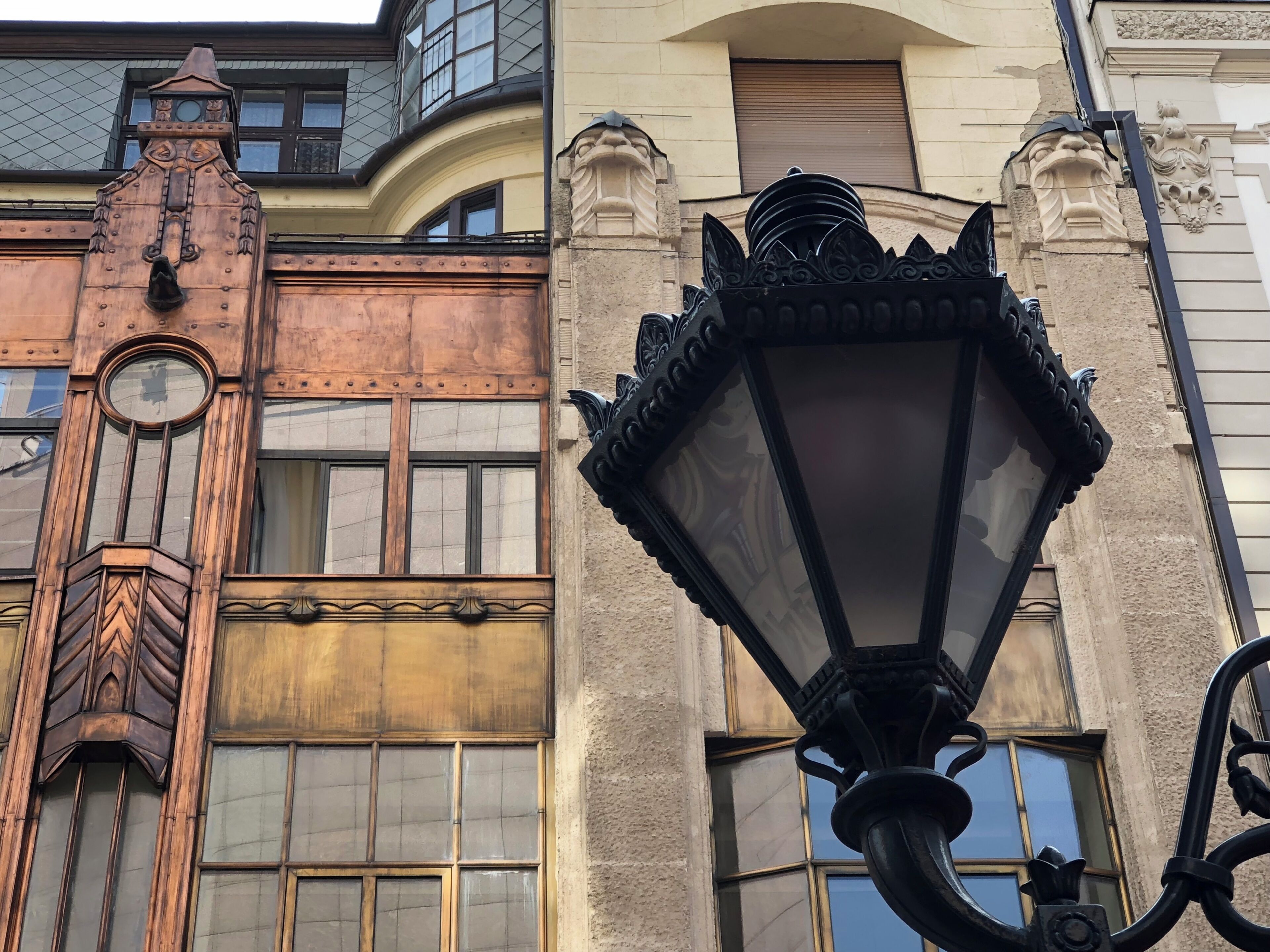 Fachada de edificio con una alta y ornamentada torre de reloj y una farola.