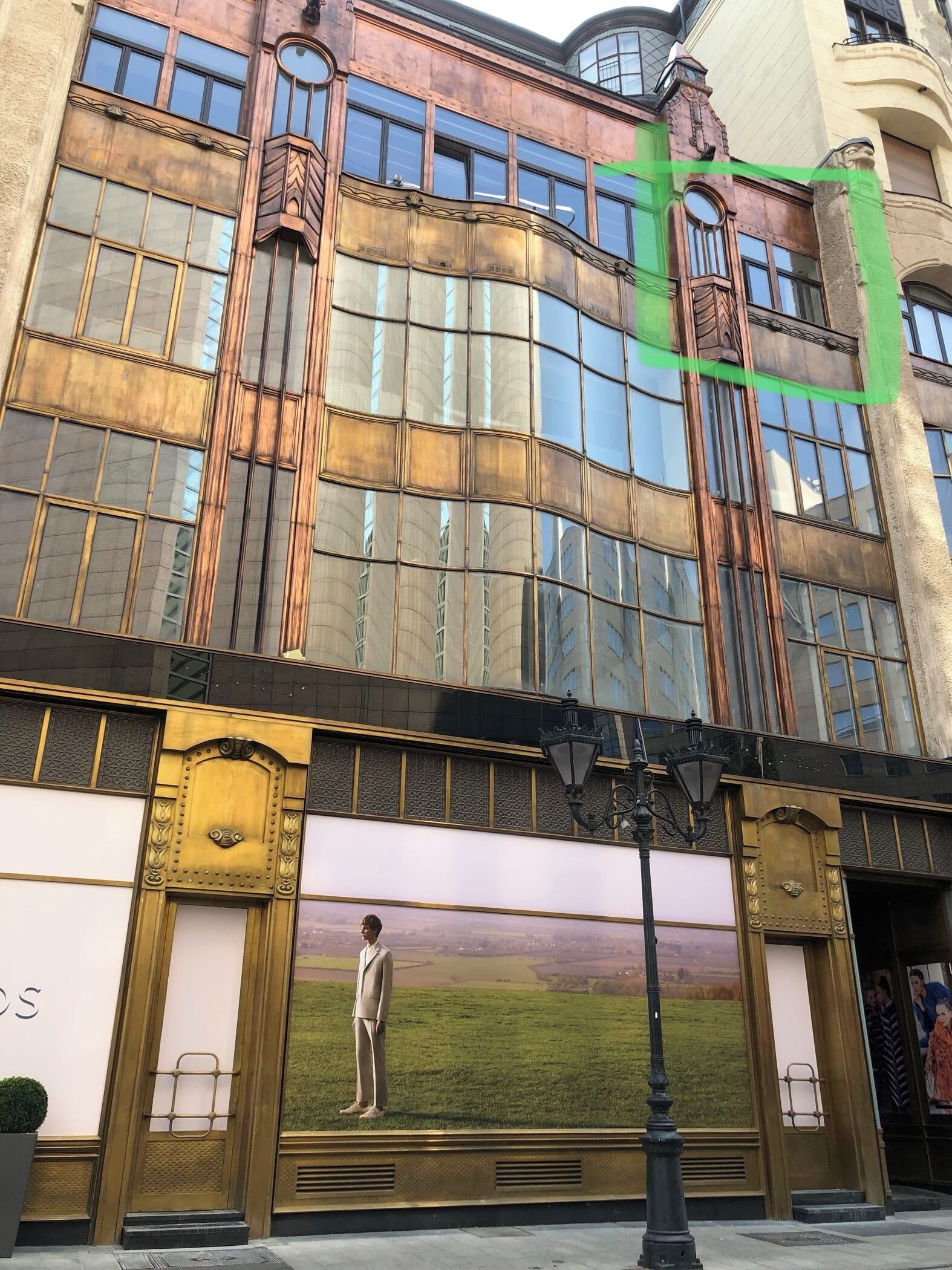 A building with large windows, a person standing in front, and a street lamp.