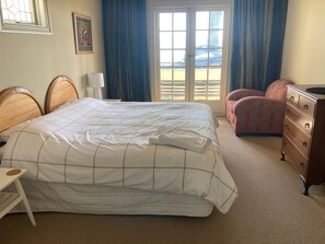 A hotel room with a bed, a dresser, a chair, a desk, a lamp, a painting, and a window with curtains. - Luxury beachfront villa perfectly located in Ahuriri Napier (Napier)