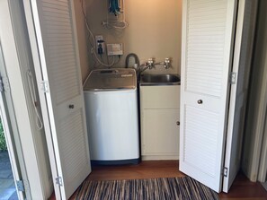 A compact laundry room with a washing machine, a sink, and a small cabinet. - Luxury beachfront villa perfectly located in Ahuriri Napier (Napier)