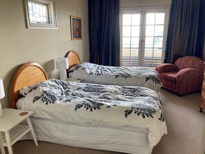 A hotel room with two beds, a chair, a small table, and a window with curtains. - Luxury beachfront villa perfectly located in Ahuriri Napier (Napier)