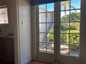 A room with a large glass door leading to a backyard with a staircase and greenery. - Luxury beachfront villa perfectly located in Ahuriri Napier (Napier)