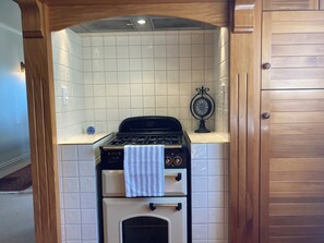 Una cocina con estufa a gas, horno y un reloj en la pared.