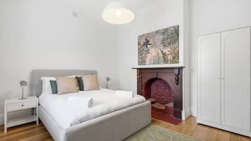 A bedroom with a bed, nightstands, a fireplace, and a wardrobe.