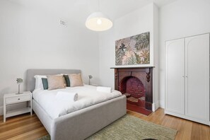 Ein Schlafzimmer mit einem Bett, Nachttischen, einem Kamin und einem Kleiderschrank.