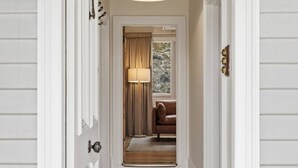 A hallway with a wooden floor, a lamp, a brown leather chair, and a window with curtains. - Sandy Bay Style | Close to CBD (Sandy Bay)