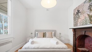 A bedroom with a bed, bedside tables, a fireplace, and a window. - Sandy Bay Style | Close to CBD (Sandy Bay)