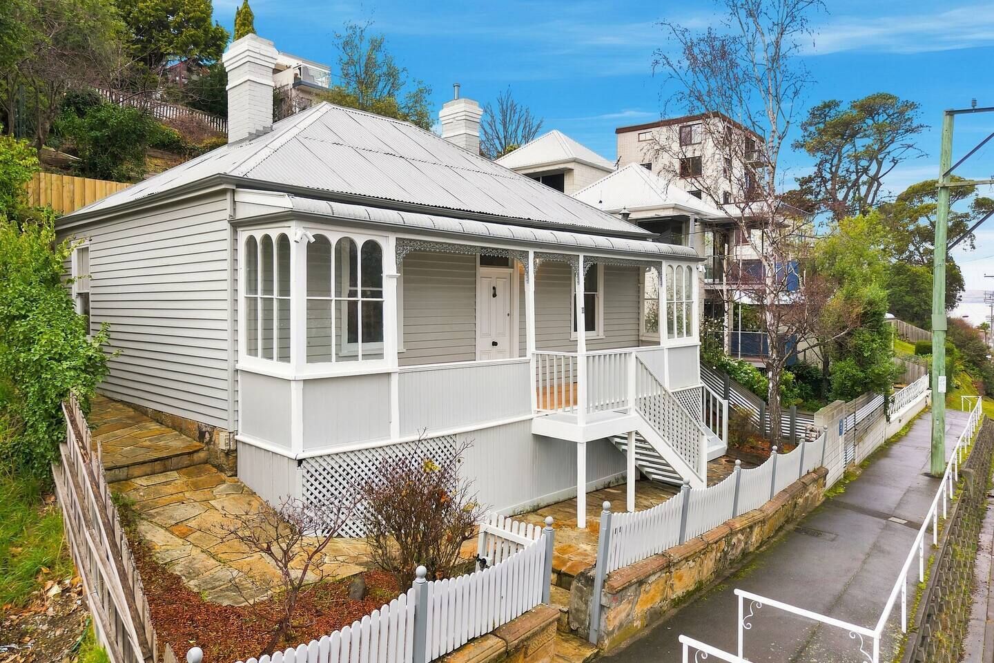 A two-story house with a porch, a stone pathway, and a white picket fence.