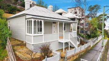 A two-story house with a porch, a stone pathway, and a white picket fence.