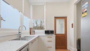 A compact kitchen with a Bosch dishwasher, a microwave, and a sink. - Sandy Bay Style | Close to CBD (Sandy Bay)