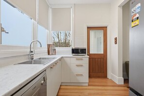 A compact kitchen with a Bosch dishwasher, a microwave, and a sink. - Sandy Bay Style | Close to CBD (Sandy Bay)