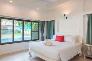 Ein Hotelzimmer mit großem Fenster, einem Bett mit weißer Bettwäsche und einem Nachttisch.