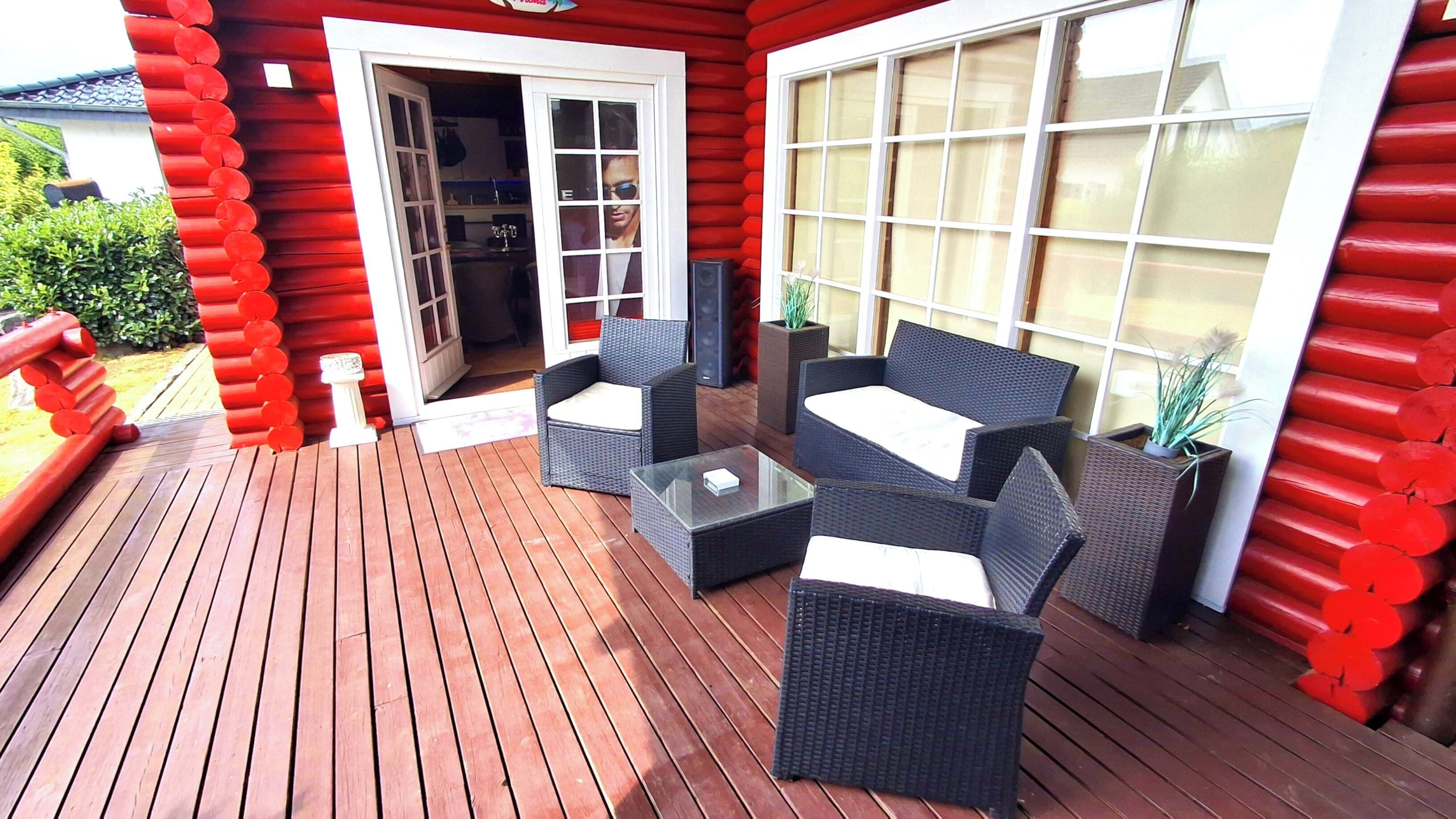 A wooden deck with wicker furniture and a glass table.