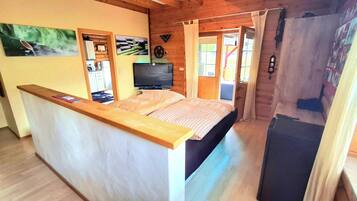 Une chambre avec un lit, une télévision, un bureau en bois et une fenêtre avec des rideaux.