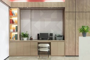 A modern office space with a desk, computer, printer, and a bookshelf with books and a plant.