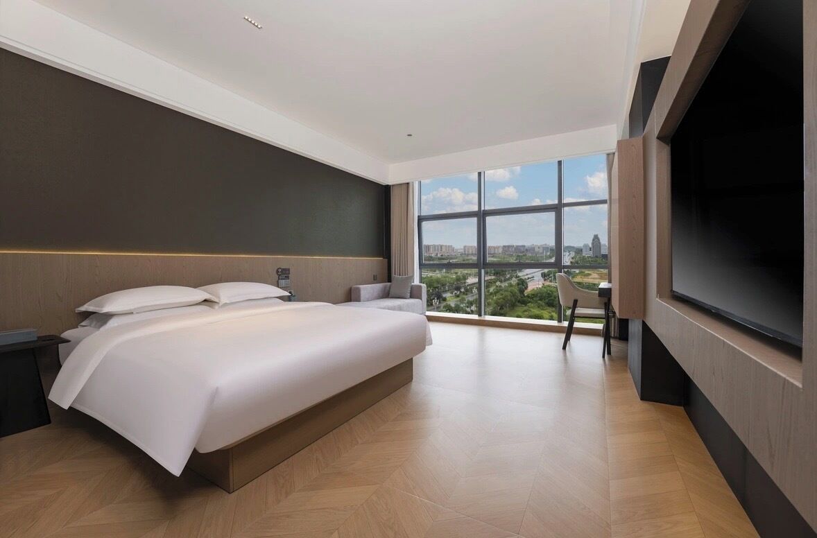 A modern hotel room with a large bed, a desk, and a TV.