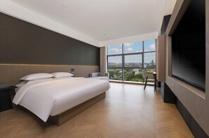 Una habitación de hotel moderna con una cama grande, televisión y vistas a la ciudad.