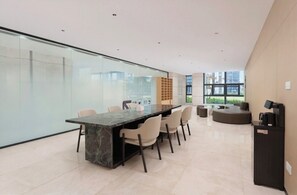 A modern interior with a marble table, chairs, a sofa, and a vending machine.