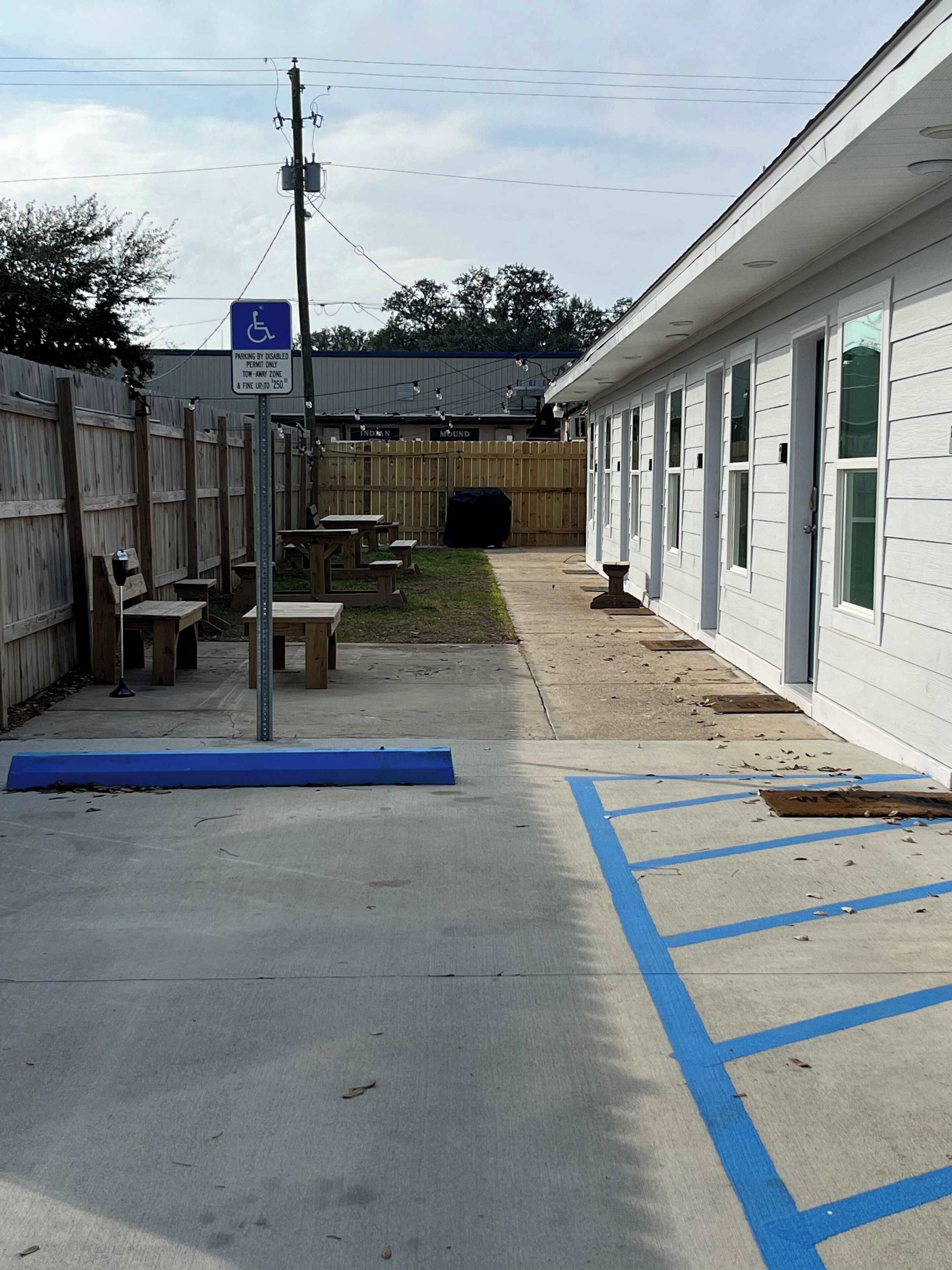 A building with a wheelchair-accessible parking area, a wooden fence, and outdoor seating.