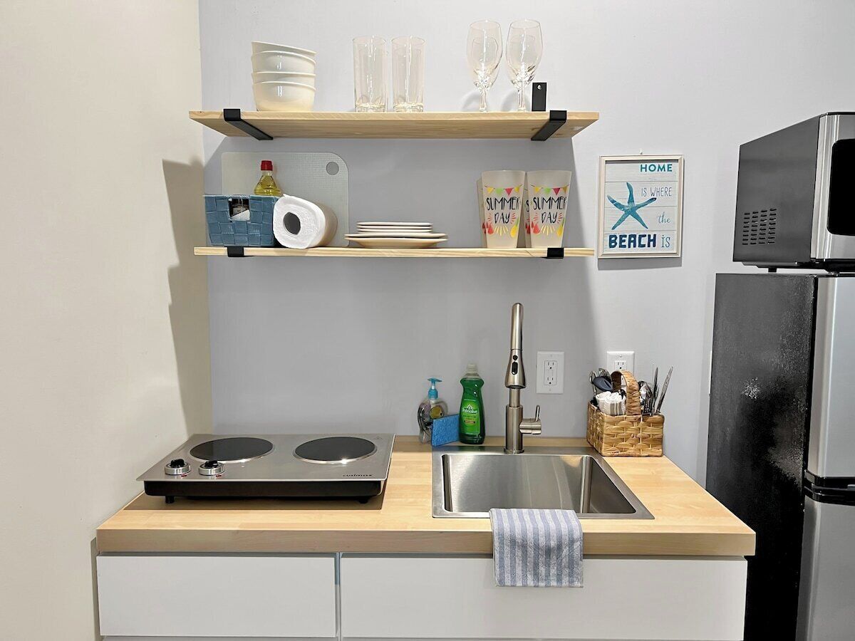A kitchen with a wooden countertop, a stainless steel sink, and a built-in microwave.