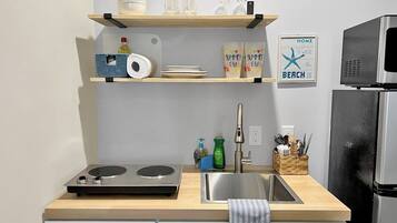 A kitchen with a wooden countertop, a stainless steel sink, and a built-in microwave.
