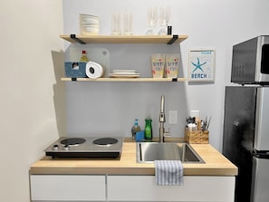 Een keuken met een houten aanrecht, een roestvrijstalen spoelbak en een ingebouwde magnetron.