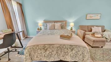 A bedroom with a bed, bedside tables, a desk, a chair, a sofa, and a rug.