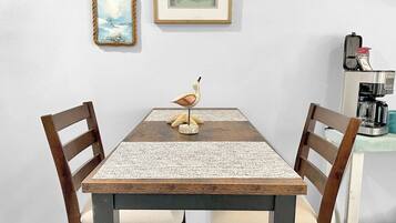 A dining table with a woven placemat, two wooden chairs, and a bird sculpture centerpiece.