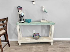 A small wooden table with a coffee maker, a teal mug, and a bird figurine. - Seaside Escape 3 - Bright Studio with Kitchenette (Fort Walton Beach)