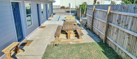 Un patio con mesas de picnic y una valla de madera.