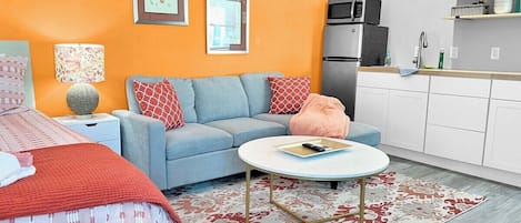 Un salon moderne avec un canapé, une table basse et un lit recouvert d’une couvre-lit à motifs.