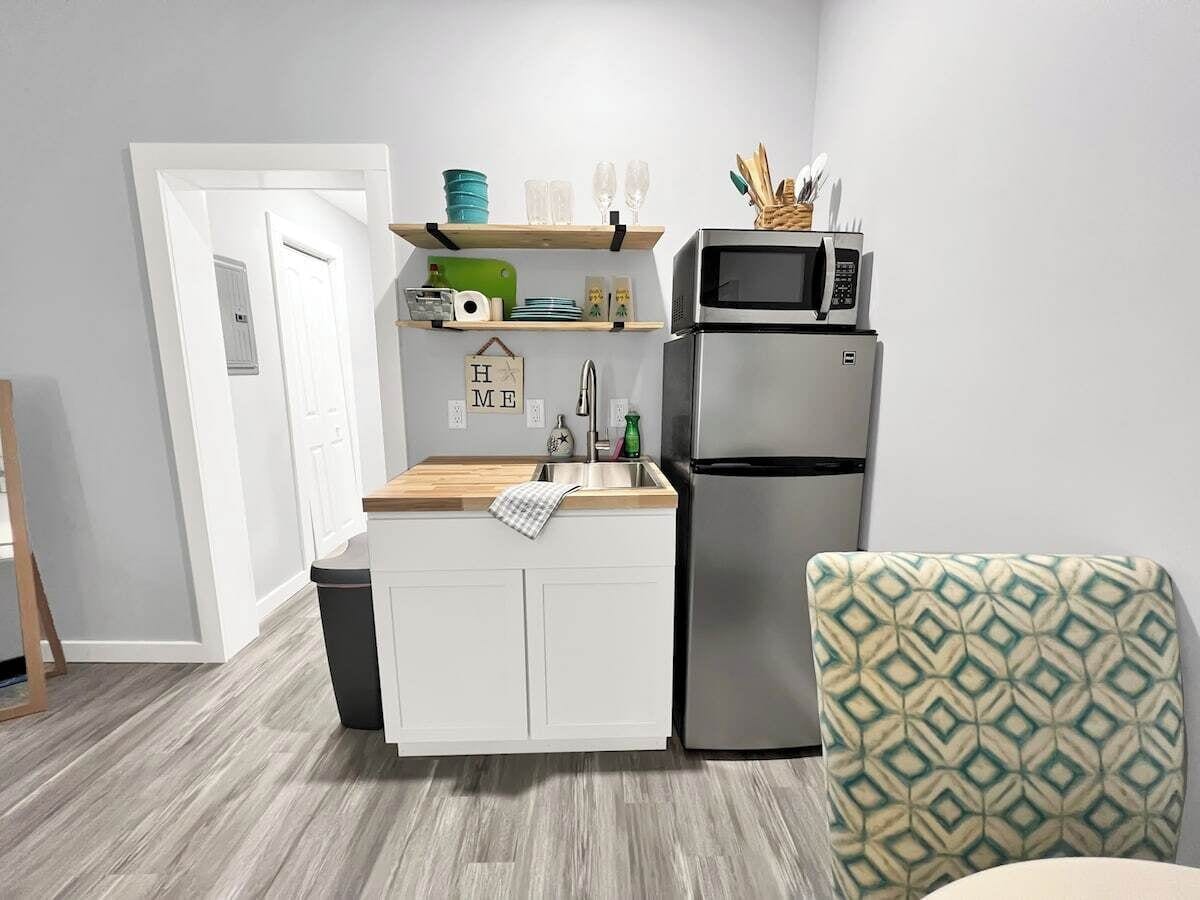 A compact kitchen with a built-in microwave, a refrigerator, and a wooden countertop.