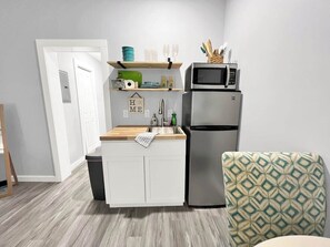 A compact kitchen with a built-in microwave, a refrigerator, and a wooden countertop. - Seaside Escape 2 - Cozy Coastal Getaway with Patio (Fort Walton Beach)