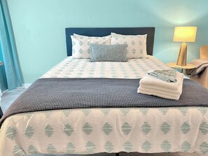 A neatly made bed with a patterned bedspread, pillows, and a folded towel. - Seaside Escape 2 - Cozy Coastal Getaway with Patio (Fort Walton Beach)