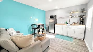 A compact living space with a kitchenette, a sofa, a dining table, and a teal accent wall.