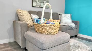 A grey sofa with a woven basket on top, a grey ottoman, and a blue accent wall.