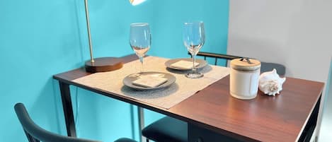 A dining table with two plates, two wine glasses, a candle, and a shell.