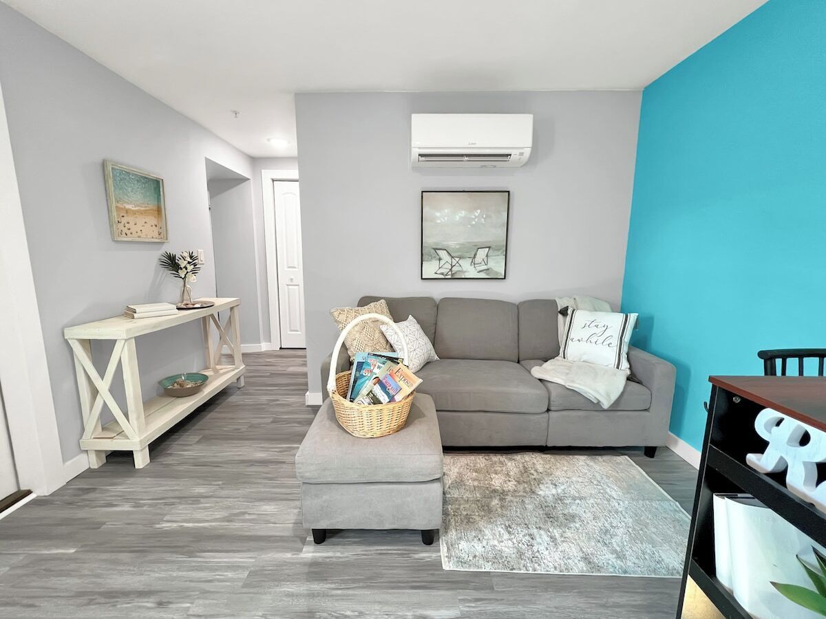 Een moderne woonkamer met een grijze bank, een bijzettafeltje en een mand met tijdschriften.