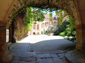 An arched stone pathway leading to a courtyard with a fountain and a building in the background. - SONBERG House - near the ÖBB Weststeiermark Train Station - free bikes (Groß Sankt Florian)