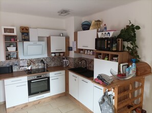 A compact kitchen with white cabinets, a built-in oven, a sink, and a microwave. - SONBERG House - near the ÖBB Weststeiermark Train Station - free bikes (Groß Sankt Florian)